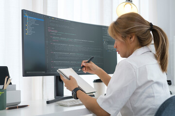 Young woman software developer working with program code on wide displays at modern office.