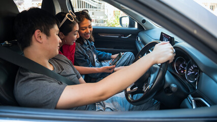 Happy Asian friends check map on GPS app on smartphone in suv car