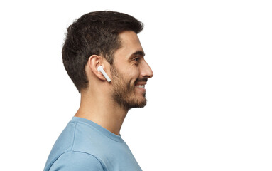 Sideways portrait of smiling young man listening to music or radio, uses modern wireless earphones,...