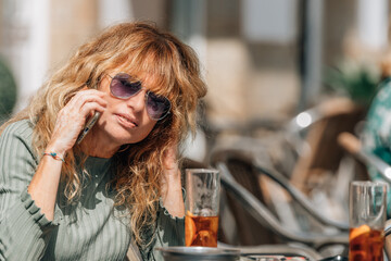 middle-aged woman talking on mobile phone on the terrace of the bar