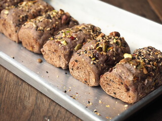 Cereal and nut crusted bread rolls in baking tray