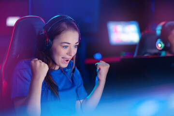 Young caucasian woman pro gamer streamer winner playing in online video game, neon color soft focus