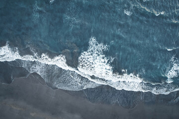 Big waves crushing on a sandy beach - blue green ocean captured with a drone - Canggu Bali
