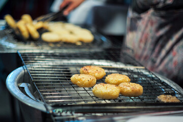 Selective focus on the buns of sticky grilled on the charcoal grill in the night flea market.