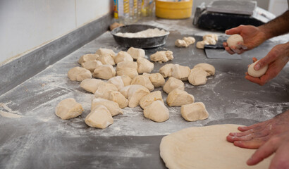 Obraz premium Hands of baker shaping and flattening dough on working surface in bakery
