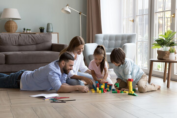Family couple of happy parents and two little son and daughter kids playing learning games on warm...