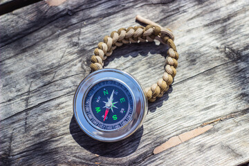 Fototapeta na wymiar paracord bracelets and navigational compass on wooden board