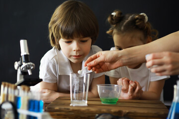 Children scientists. Schoolchildren in the laboratory conduct experiments. Boy and girl experiments with a microscope.