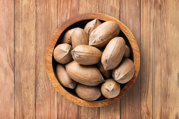 shelled pecan nuts raw in bowl on wooden table background, top view. organic vegetarian food.