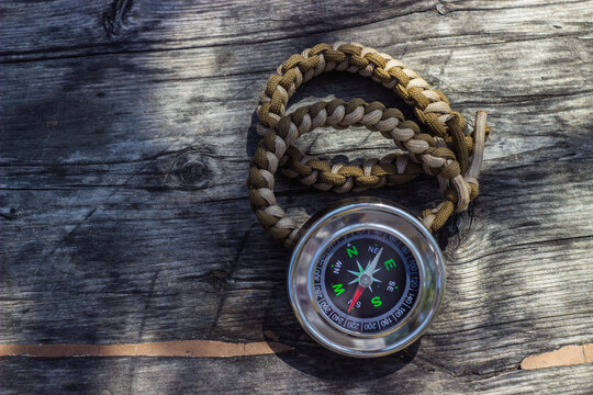 paracord bracelets and navigational compass on wooden board
