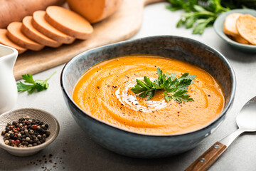 Sweet potato cream soup in a ceramic bowl on a light background, selective focus - obrazy, fototapety, plakaty