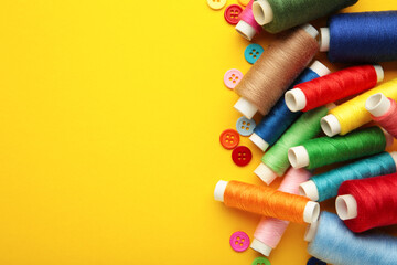 Colorful buttons with colorful thread on yellow background.