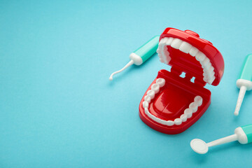 Funny toy teeth with eyes and toothbrush on blue background.