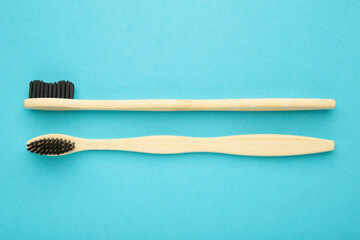 Bamboo wooden toothbrush with black brush bristles on blue background