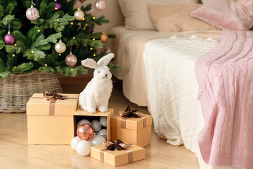 New Year's decor of a bedroom in the Scandinavian style. White plush rabbit sits on gifts against...