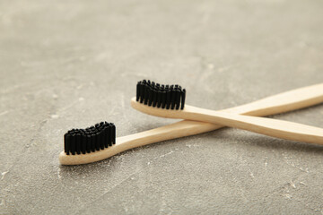 Bamboo wooden toothbrush with black brush bristles on grey background.