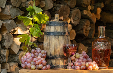 Rose wine in the wineglass and ripe grapes on wooden table. Grape harvest. Wine tasting culture. Sommelier pouring dessert wine in glass. Winery
