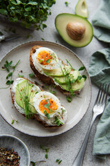 Bread toast, boiled eggs, avocado slice, microgreens on a plate