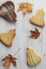 Cookies shaped like pumpkin and leaves on rustic wood background