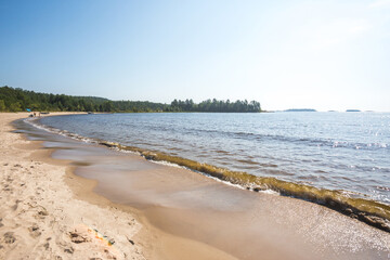 Fototapeta na wymiar Sandy beach on the Koyonsaari Island. Ladoga Lake waves. Karelia Republic, Russia