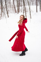 beautiful smiling happy woman in red long dress having fun with snow in winter forest