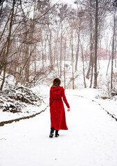 beautiful smiling happy woman in red long dress having fun with snow in winter forest