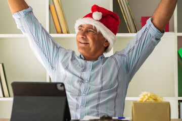 man with santa hat in the office celebrating christmas with victory gesture