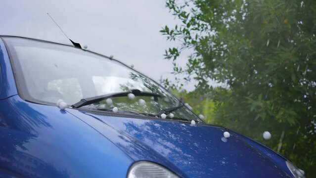 large hail during a storm causes damage to a parked car