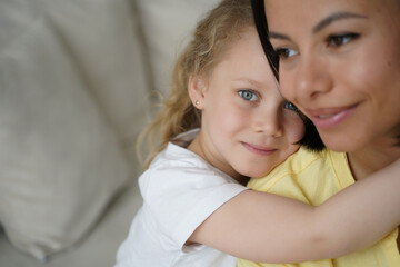 Adopted child preschooler girl daughter hugging mom, enjoy cuddles. Happy childhood, adoption