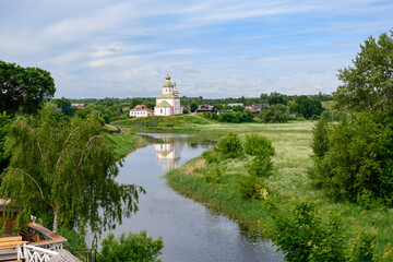 View of the Kamenka River, Ilyinsky Church built in 1744 and blooming meadows in summer in Suzdal, Russia