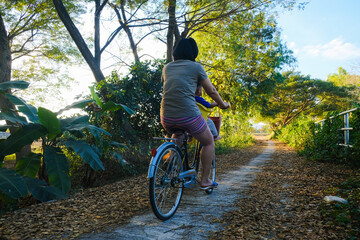 Little boy sitting on bike chair ride bicycle with mother in park sunset