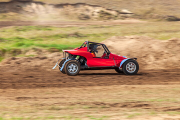 Fototapeta na wymiar A small sports blurred buggy on a rally competition track during weekend training on a warm summer day.