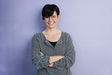 Business woman in front of purple wall laughs into camera. copy space
