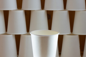 Paper cups stacked on top of each other against a wooden wall. Texture from disposable tableware. Ecological disposable tableware