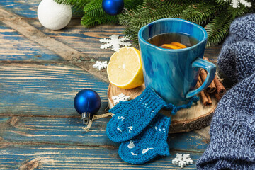 Hot drink with crocheted funny mittens. Traditional winter decor, fir tree branches, snowflakes