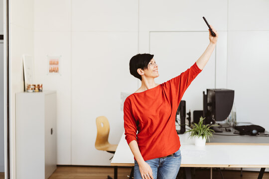 Businesswoman takes a selfie with her cell phone in the office