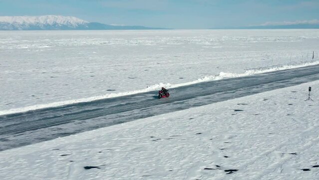 Aerial view of biker on the background of winter landscape. Get the speed record on the motorcycle at a distance of one mile on an ice track on the frozen lake Baikal