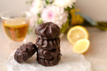 Beautiful delicious chocolate marshmallows on a white table with lemon and tea