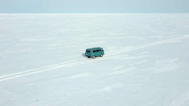 the vehicle uaz bukhanka rides in minimalistic winter landscape of edless flat snowy field