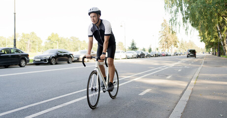 A male cyclist in a helmet rides a bicycle, training in the city.