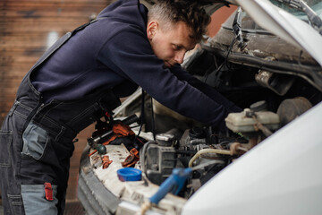 male car service worker repairs a van with an open hood. - Powered by Adobe