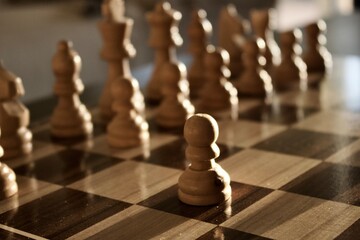 Peón de ajedrez con el resto de figuras iluminadas de fondo.