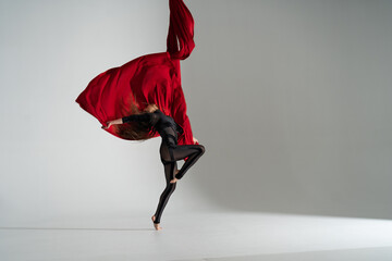 Flexible woman performs on the aerial silk on white background. Concept of originality, creativity...