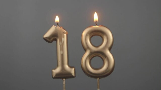 Burning gold birthday candles on gray background, number 18