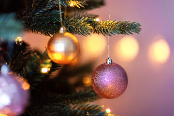Christmas balls hang on a branch of a New Year's tree. Christmas decor close up. Shiny Christmas toys and lights.