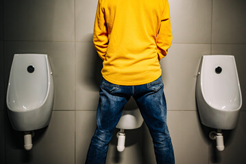 back Man peeing to toilet bowl in restroom - obrazy, fototapety, plakaty