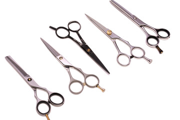 Professional hairdressing scissors for cutting and thinning hair lie in a row. Isolated on white...