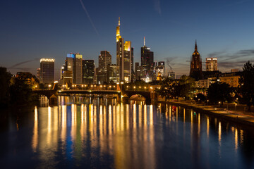 Fototapeta na wymiar Frankfurt skyline and Alte Brücke bridge at night with reflection in the Main river in the foreground, taken from the Ignatz-Bubis bridge