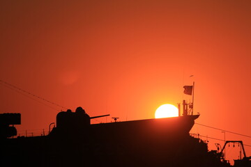Sunset over the silhouette army ship