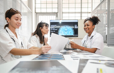 Diverse group female doctors meeting looking at medical x-ray then diagnosis and discussing before...